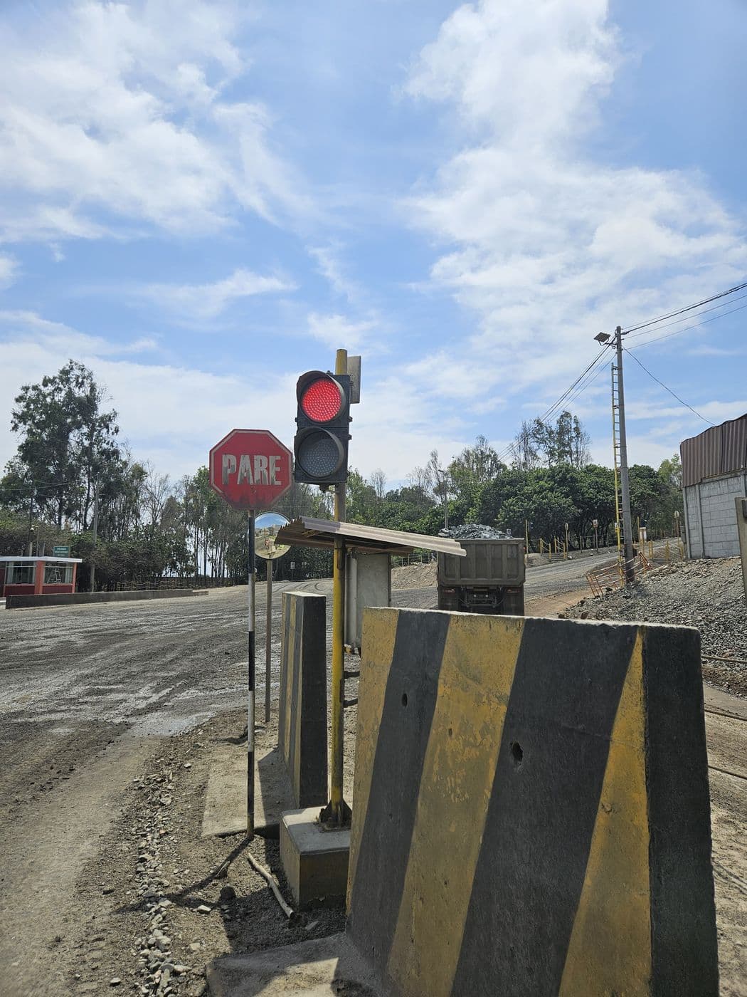 Semáforo de seguridad en rojo junto a una señal de PARE, deteniendo el paso en un cruce de operación.