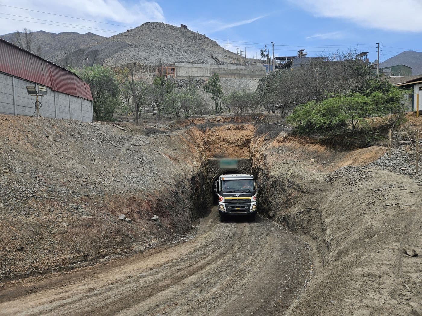 Un volquete sale por la bocamina de una mina subterránea a través de un túnel revestido en piedra.